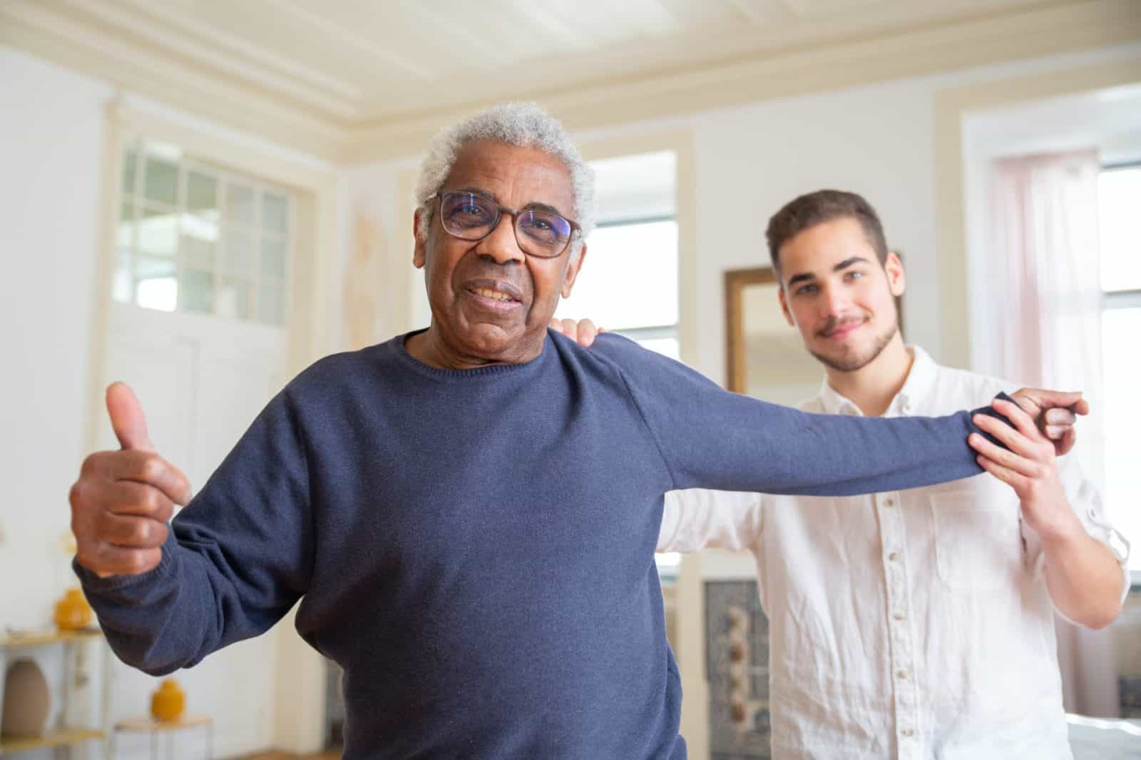 a man giving a thumbs-up while a physical therapist helps him stretch