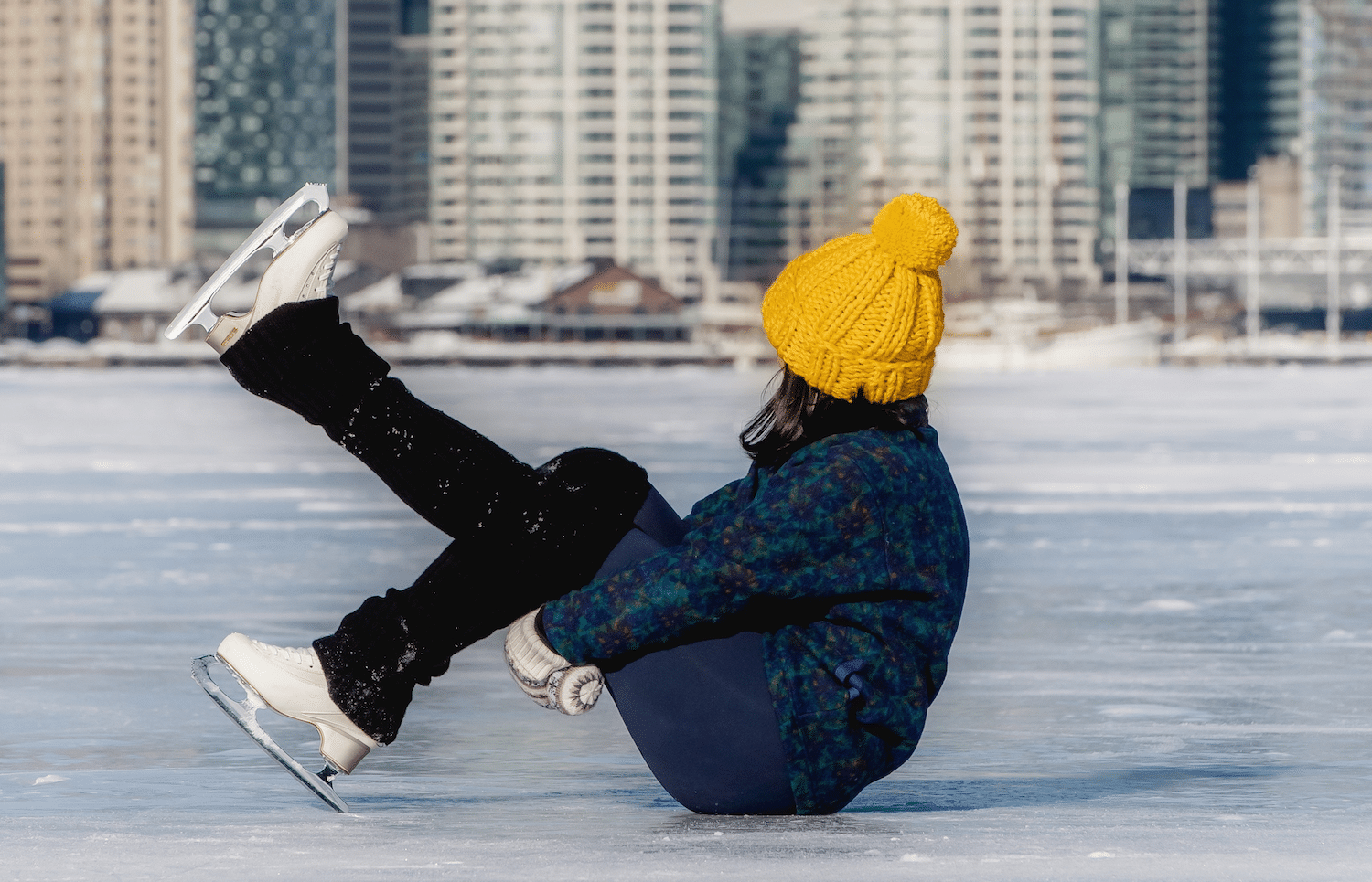 a person wearing figure skates sitting on a frozen lake