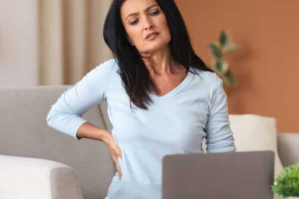 woman having back pain while using laptop