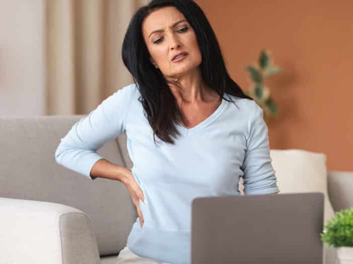 woman having back pain while using laptop