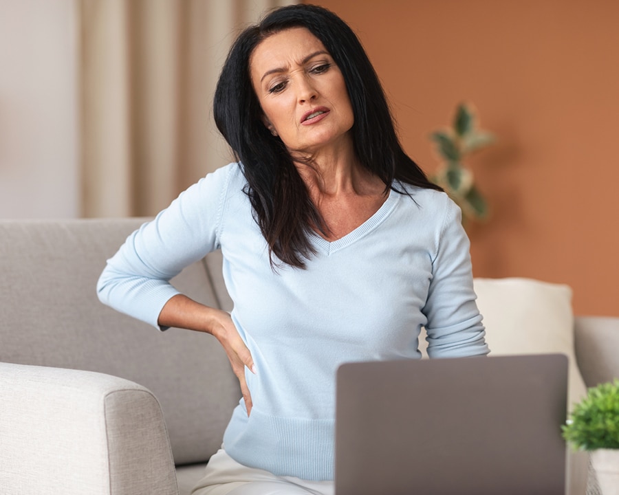 woman having back pain while using laptop