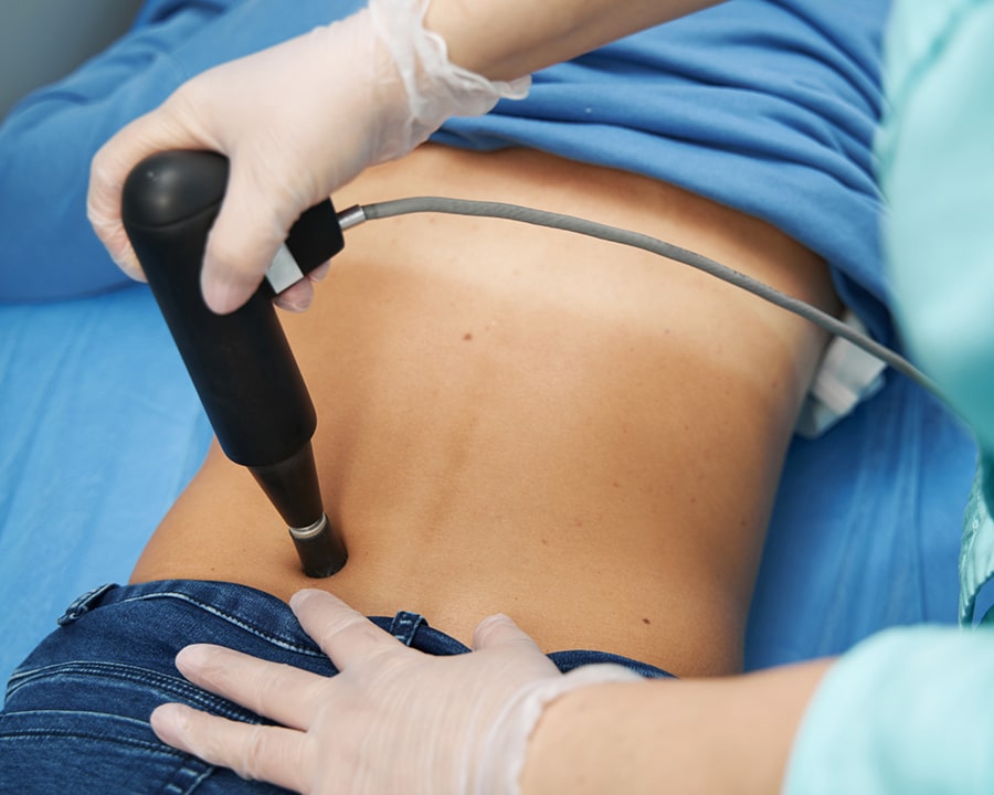 Female patient receiving extracorporeal shockwave therapy in clinic