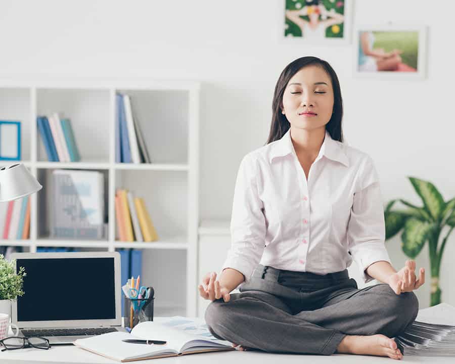 de-stress-with-physical-therapy lady meditating on her desk