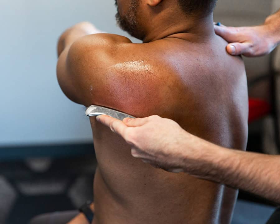 physical therapist using the graston technique on the shoulder to help with chronic pain