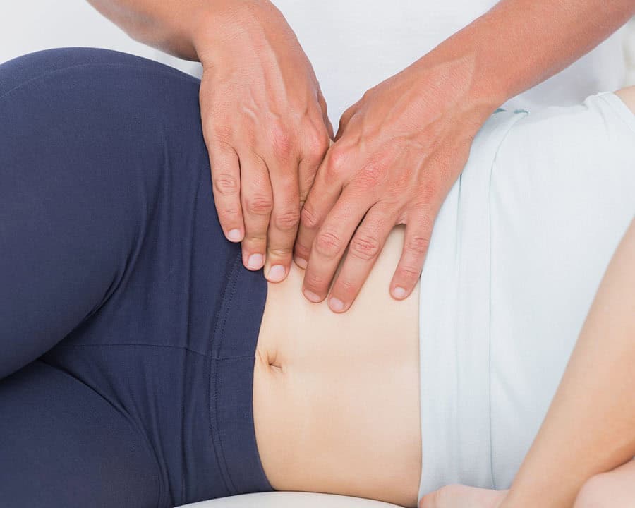 hips and tummy of a lady, with therapists hands working on her hips