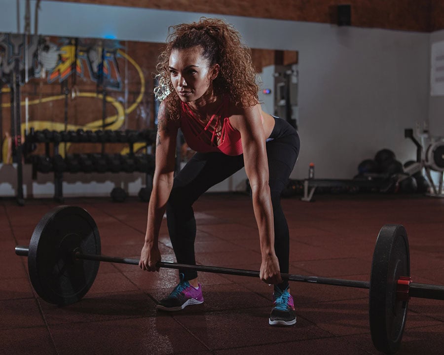 woman with strong athletic body doing deadlift exercise with barbell