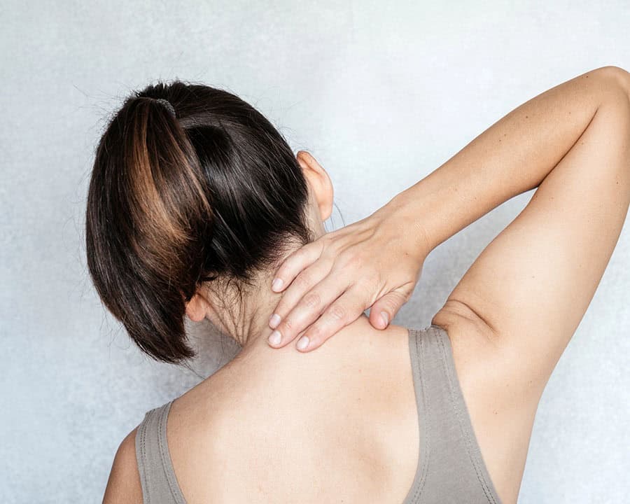 A woman touching her neck with her hand, neck pain, neck pain relief exercises