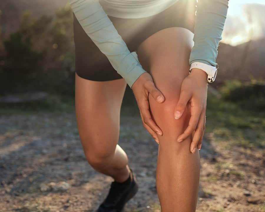 a woman massaging her knee after an injury occured.