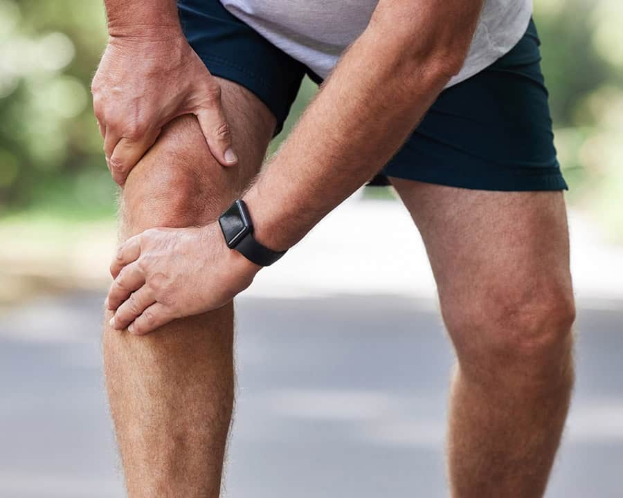 Closeup shot of an unrecognisable man experiencing knee pain while exercising outdoors.